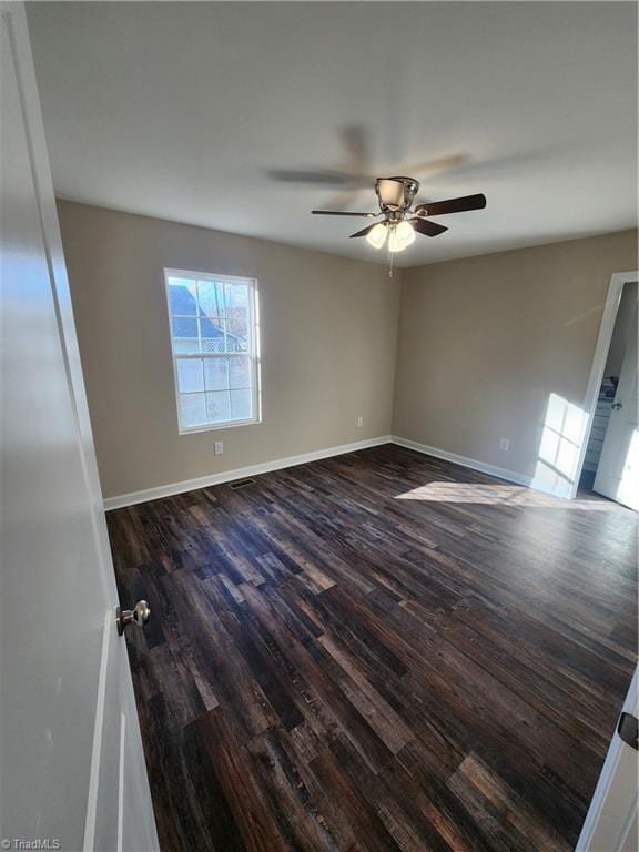 spare room with dark hardwood / wood-style flooring and ceiling fan