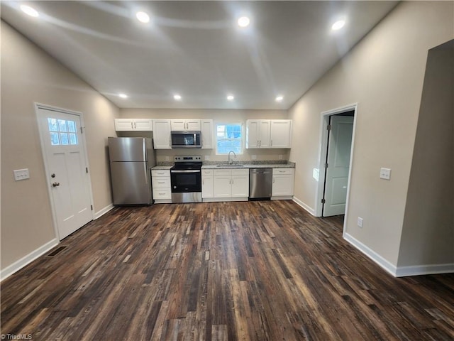 kitchen featuring lofted ceiling, sink, appliances with stainless steel finishes, dark hardwood / wood-style flooring, and white cabinetry