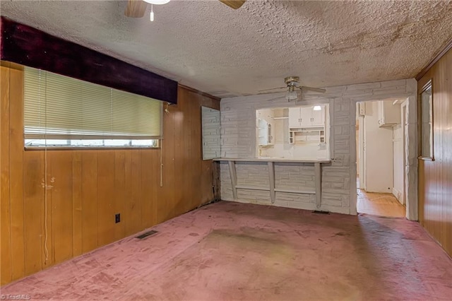 1900 Peachtree St, Winston-Salem, NC 27107 - unfurnished living room featuring a ceiling fan, wood walls, and a textured ceiling