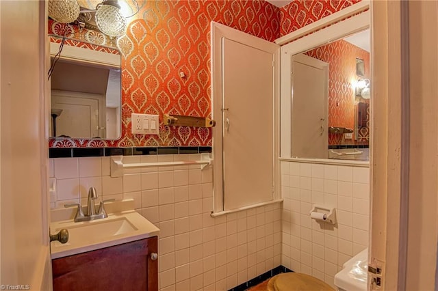 1900 Peachtree St, Winston-Salem, NC 27107 - half bath with tile walls, wallpapered walls, vanity, toilet, and a wainscoted wall