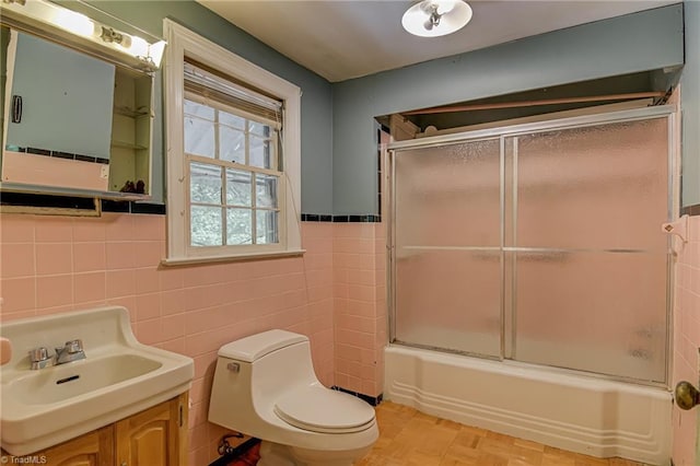 1900 Peachtree St, Winston-Salem, NC 27107 - bathroom featuring tile walls, toilet, bath / shower combo with glass door, vanity, and wainscoting