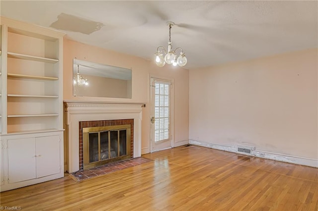 1900 Peachtree St, Winston-Salem, NC 27107 - unfurnished living room with a chandelier, light wood-style floors, and a brick fireplace