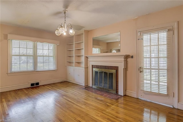 1900 Peachtree St, Winston-Salem, NC 27107 - unfurnished living room featuring a chandelier, wood finished floors, a fireplace, and baseboards