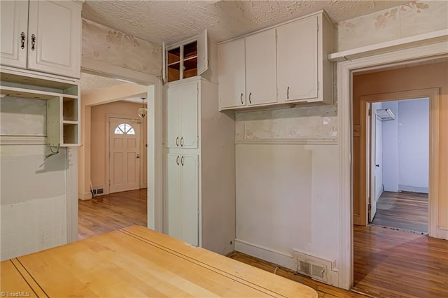 1900 Peachtree St, Winston-Salem, NC 27107 - kitchen featuring wood finished floors, white cabinetry, a textured ceiling, light countertops, and wallpapered walls