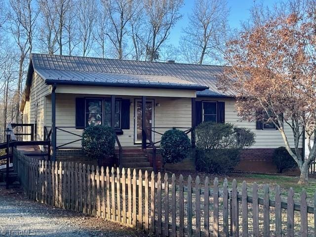 ranch-style home with metal roof, a fenced front yard, and a porch