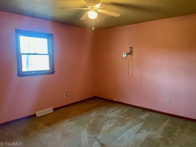 spare room with baseboards, carpet, visible vents, and a textured ceiling