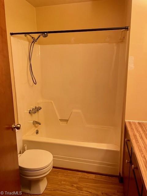 bathroom featuring toilet, vanity, wood finished floors, and bathing tub / shower combination