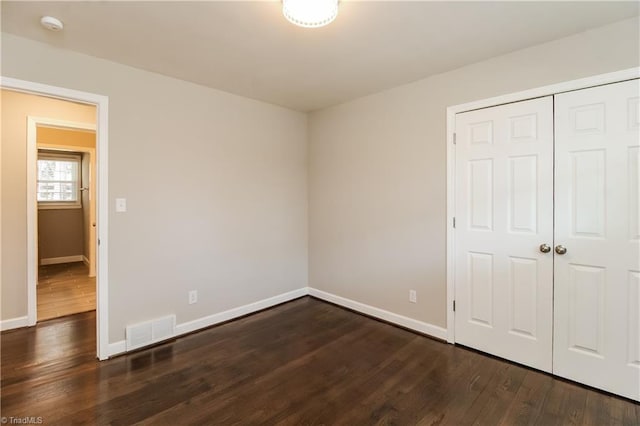 3027 Kinnamon Rd, Winston-Salem, NC 27104 - unfurnished bedroom featuring baseboards, dark wood-type flooring, and a closet