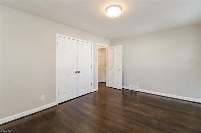 3027 Kinnamon Rd, Winston-Salem, NC 27104 - unfurnished bedroom featuring baseboards, dark wood-type flooring, and a closet