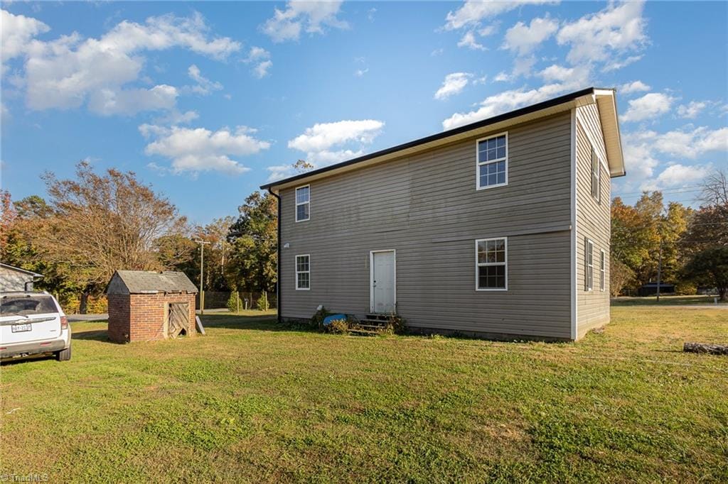 rear view of property with a storage shed and a lawn