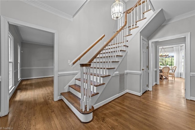 1203 Westminster Dr, Greensboro, NC 27410 - staircase featuring a chandelier, wood finished floors, and crown molding