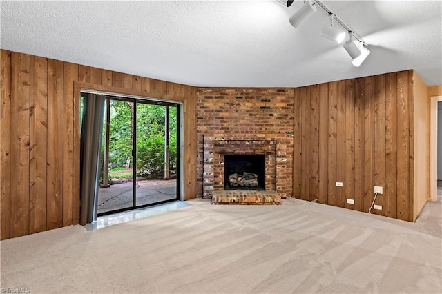 881 Brookleigh Ct, Winston-Salem, NC 27104 - unfurnished living room featuring wooden walls, carpet, track lighting, a fireplace, and a textured ceiling