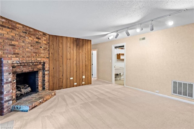 881 Brookleigh Ct, Winston-Salem, NC 27104 - unfurnished living room featuring carpet flooring, a brick fireplace, track lighting, wood walls, and baseboards
