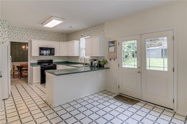 4317 Bradbury Way, High Point, NC 27265 - kitchen featuring black appliances, a peninsula, dark countertops, wallpapered walls, and white cabinetry