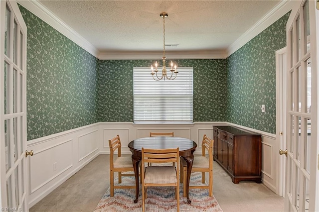 4317 Bradbury Way, High Point, NC 27265 - carpeted dining space with crown molding, a chandelier, a wainscoted wall, and a textured ceiling