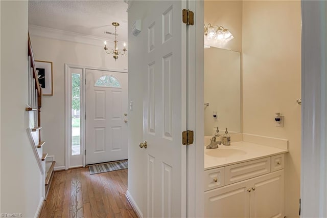 4317 Bradbury Way, High Point, NC 27265 - entrance foyer with light wood-style flooring, crown molding, stairway, a chandelier, and a textured ceiling
