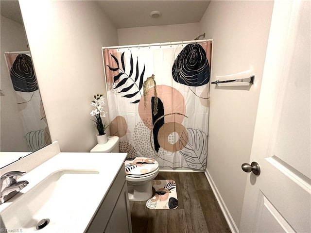 bathroom with baseboards, a shower with shower curtain, toilet, vanity, and wood finished floors