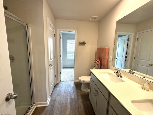 bathroom featuring a stall shower, wood finished floors, a sink, and visible vents