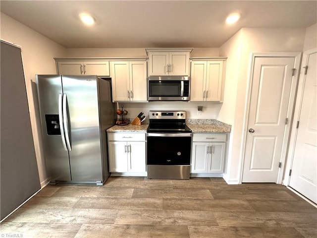 kitchen with stainless steel appliances, recessed lighting, light wood-style flooring, and light stone counters