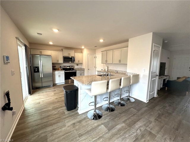 kitchen featuring light wood-type flooring, a kitchen breakfast bar, a peninsula, and stainless steel appliances
