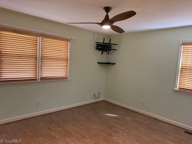 empty room featuring baseboards, wood finished floors, and a ceiling fan