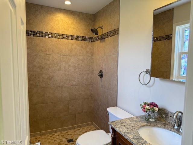 full bath with vanity, toilet, and tiled shower