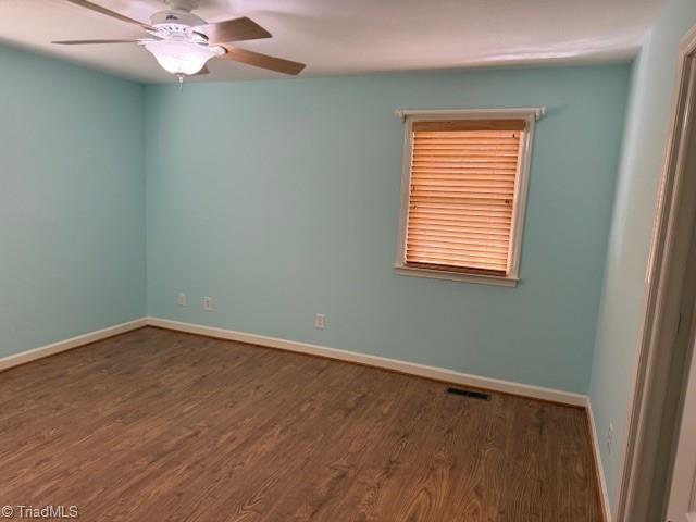 spare room with visible vents, baseboards, and wood finished floors