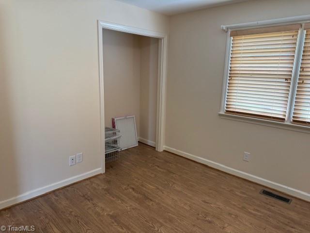 unfurnished bedroom featuring visible vents, baseboards, and wood finished floors