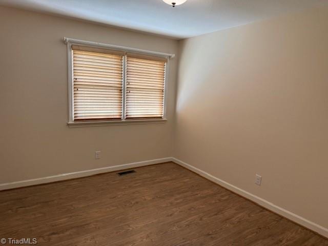 spare room with visible vents, baseboards, and wood finished floors