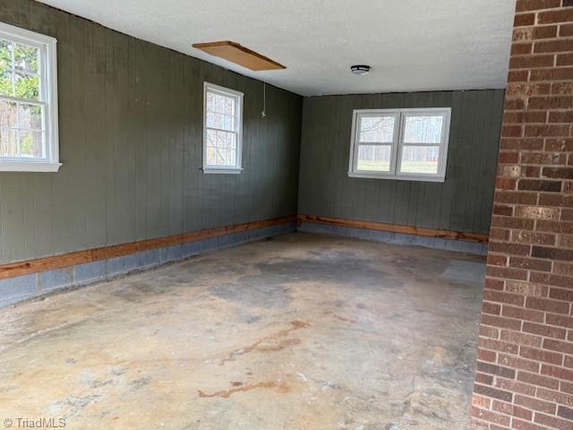 spare room featuring wooden walls and unfinished concrete flooring