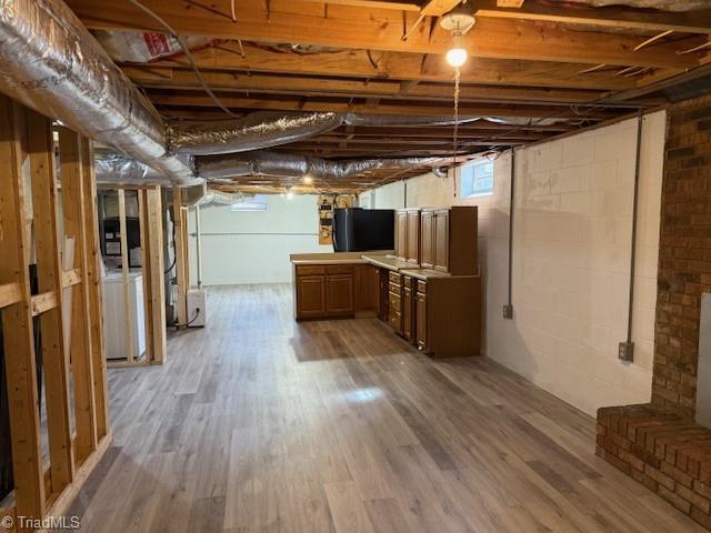 below grade area with light wood-style flooring and washer / clothes dryer