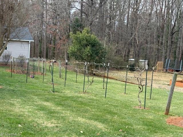 view of yard with a trampoline and fence