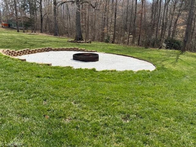 view of yard featuring a wooded view and an outdoor fire pit