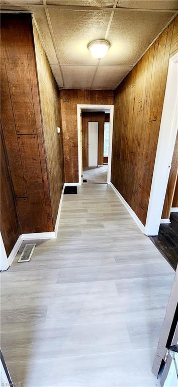 hall featuring wooden walls and light hardwood / wood-style floors