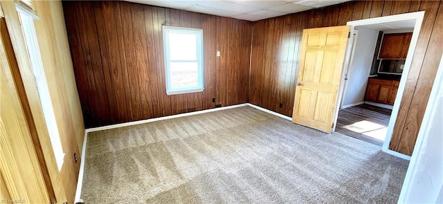 carpeted spare room with wood walls