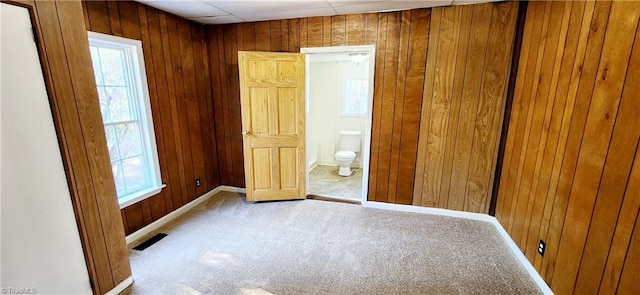 unfurnished bedroom with connected bathroom, wood walls, a paneled ceiling, and light carpet