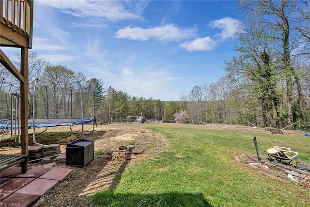 view of yard featuring a wooded view and a trampoline