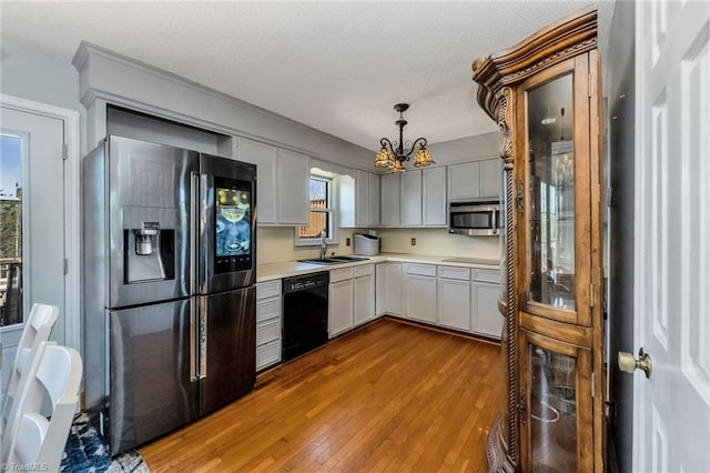 kitchen featuring a textured ceiling, light countertops, a chandelier, wood finished floors, and black appliances