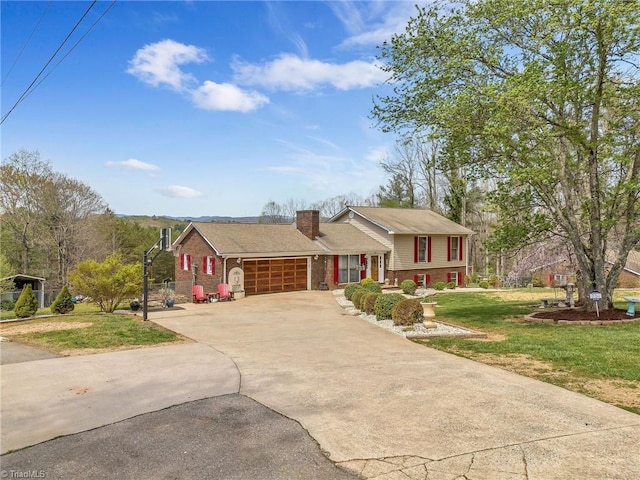 split level home with driveway, a front yard, a chimney, an attached garage, and brick siding