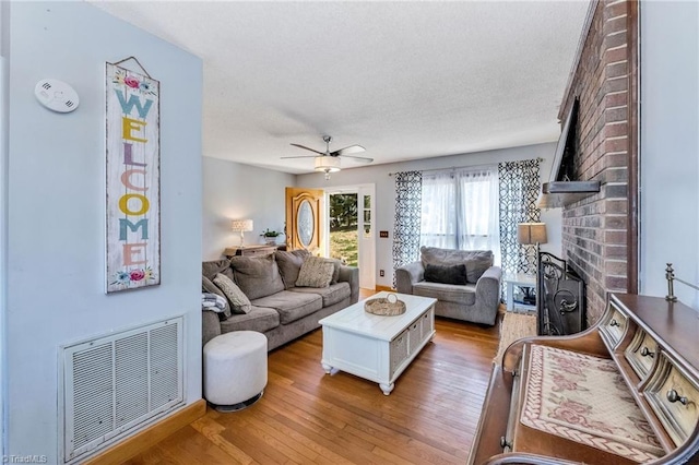 living area featuring a textured ceiling, visible vents, light wood-style floors, and a ceiling fan