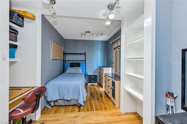 bedroom with rail lighting and wood finished floors