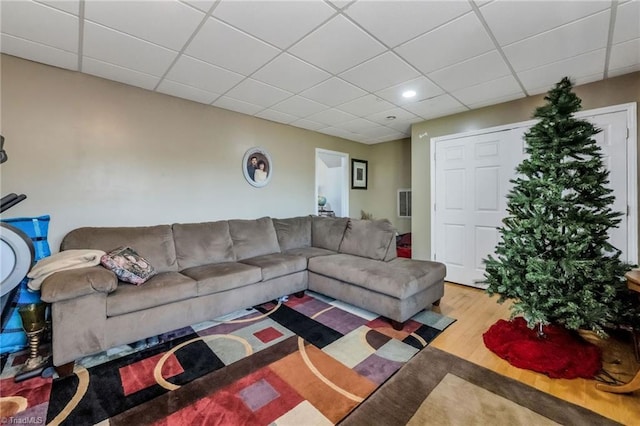 living area with a drop ceiling and wood finished floors