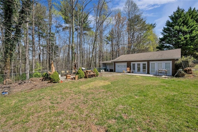 view of yard featuring french doors, a garage, and fence