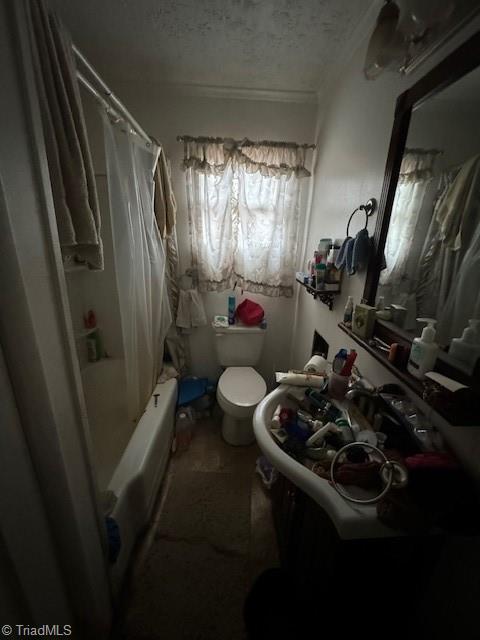 bathroom with shower / bath combo, a textured ceiling, and toilet