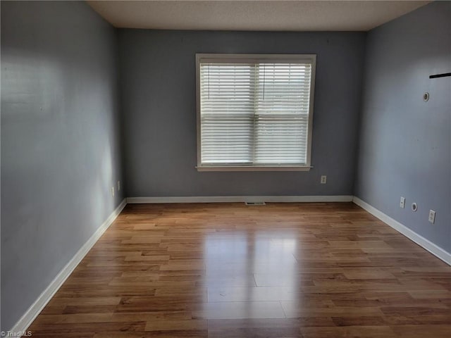 unfurnished room with visible vents, baseboards, and wood finished floors