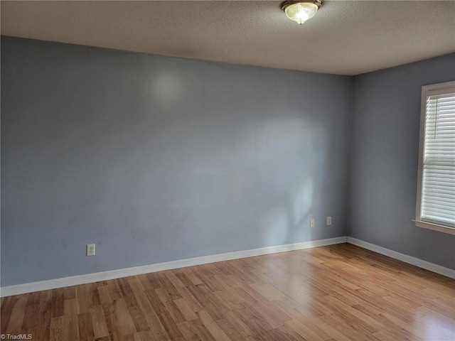 spare room featuring wood finished floors, baseboards, and a textured ceiling