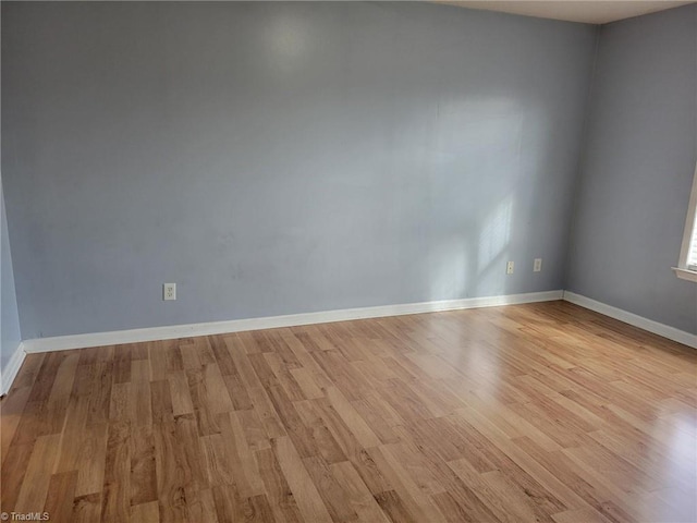 spare room featuring light wood-type flooring and baseboards