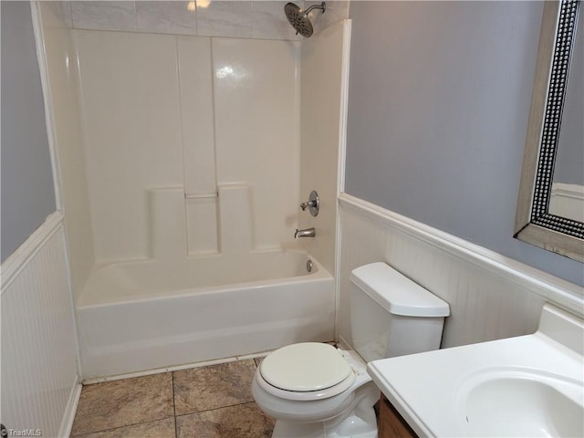 full bath with a wainscoted wall, toilet, tub / shower combination, and vanity