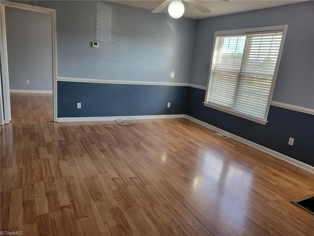 unfurnished room featuring visible vents, wood finished floors, baseboards, and ceiling fan