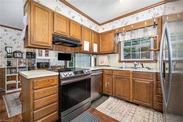 6215 Russwood Dr, Pleasant Garden, NC 27313 - kitchen with appliances with stainless steel finishes, wallpapered walls, ornamental molding, under cabinet range hood, and brown cabinetry